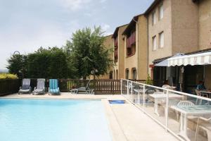 a swimming pool with chairs and tables next to a building at Brit Hotel Vallee du Lot in Fumel