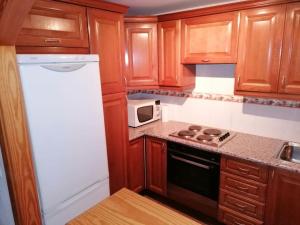 a kitchen with wooden cabinets and a white refrigerator at Buganvillas Urbanisation House Facing Pool in Vera