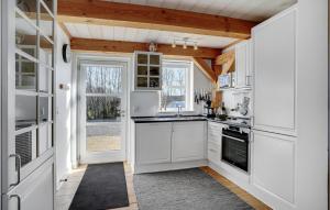 a kitchen with white cabinets and an open door at Two-Bedroom Holiday Home In Blavand in Blåvand