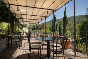 een patio met tafels en stoelen met bergen op de achtergrond bij Auberge de l'Escargot d'Or in Dieulefit