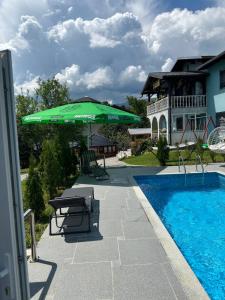 a patio with a green umbrella next to a pool at PRENOCiSTE SARA in Bihać