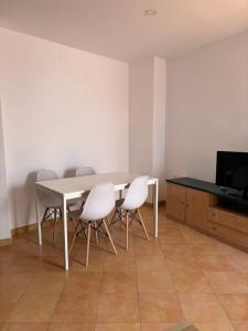 a dining room table with white chairs and a television at Asís 20 in Medina Sidonia