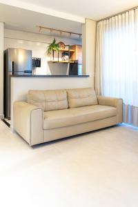 a couch in a living room with a kitchen at PALMAS EXPERIENCE - FLAT ACONCHEGANTE no centro in Palmas