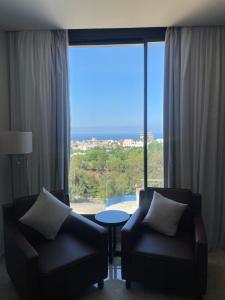 a living room with two chairs and a large window at 365 UrbanLiving in Jbeil