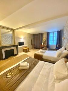 a large hotel room with two beds and a fireplace at Logis Grand Hôtel De L'Europe in Langres +8 photos