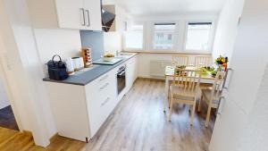 a kitchen with white cabinets and a table and chairs at Fewo Seenah in Radolfzell am Bodensee