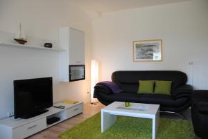 a living room with a black couch and a tv at Ferienwohnung direkt in Sassnitz in Sassnitz