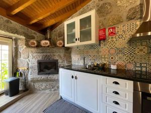 una cucina con armadi bianchi e un muro in pietra di Quinta do Paço - Casa do Caseiro a Vila Verde