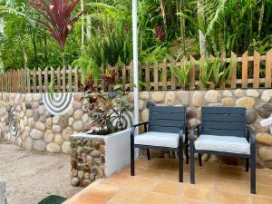 two blue chairs sitting next to a stone wall at Nan La Tigra in El Rosario