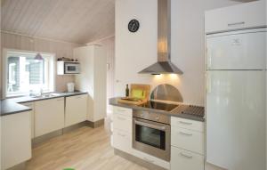 a kitchen with white cabinets and a stainless steel refrigerator at Holiday Home Gråpilevej in Bøtø By +5 photos