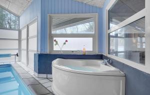 a blue bathroom with a tub and a window at Nice Home In Glesborg With Sauna in Fjellerup Strand
