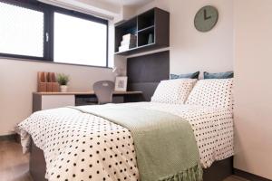 una camera da letto con un letto con un orologio a parete di Canvas Capital House in Southampton a Southampton