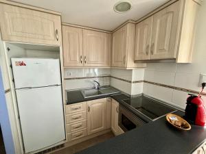 a kitchen with wooden cabinets and a white refrigerator at Faro de Cullera I in Faro de Cullera +6 photos