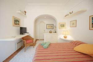 a white bedroom with a bed and a desk at La Piccola, Capri in Capri
