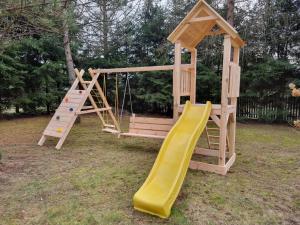 a wooden playground with a slide and a swing at Dom na mazurach in Jerutki