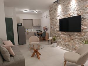 a living room with a tv on a brick wall at Wave Vibes in Hersonissos