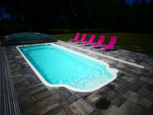 a swimming pool with pink chairs and a swimming pool at Ignaszówka 123 in Radawa