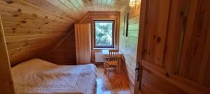 a bedroom in a log cabin with a bed and a desk at Dom na mazurach in Jerutki