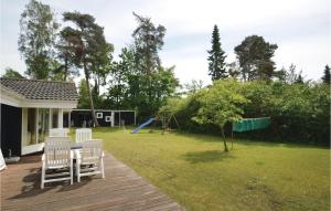 a deck with chairs and a playground in a yard at Three-Bedroom Holiday Home In Vaggerlose in Marielyst
