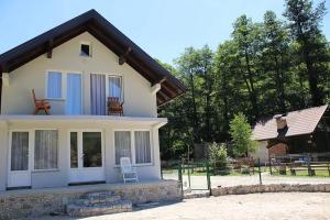 a white house with a chair on the porch at Vikendica Gajić in Šipovo
