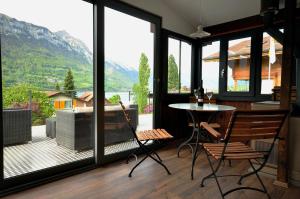 um quarto com uma mesa e cadeiras e uma grande janela em Lake View Chalet em Bönigen