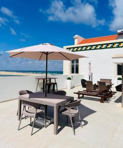 a table and chairs with an umbrella on a patio at Foz Beach House - Rooftop & Sea view in Foz do Arelho