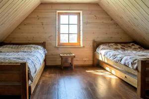 two beds in a log cabin with a window at Barškulių Sodyba in Ricieliai