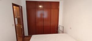 a bedroom with a wooden cabinet next to a bed at EnVIVEIRO Destino Playa de Covas in Viveiro