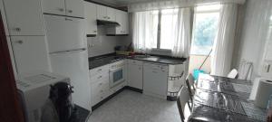 a small kitchen with white appliances and a window at EnVIVEIRO Destino Playa de Covas in Viveiro