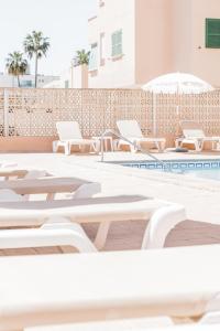 a row of lounge chairs and a swimming pool at Hotel Golf Beach in Santa Ponsa