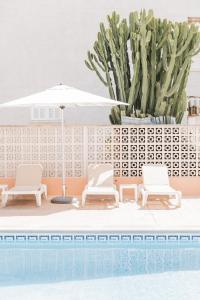 a pool with two chairs and an umbrella and cactus at Hotel Golf Beach in Santa Ponsa