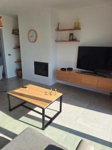 a living room with a coffee table and a flat screen tv at zonnig vernieuwd penthouse dicht bij het strand in Knokke-Heist