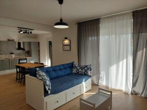 a living room with a blue couch and a kitchen at Apartman Zlata in Pakoštane