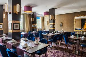 un restaurant avec des tables, des chaises et un miroir dans l'établissement Hôtel Le Versailles, à Versailles