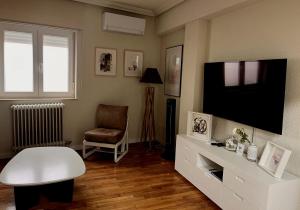 a living room with a flat screen tv and a chair at VUT PLAZA DEL ANGEL in Salamanca