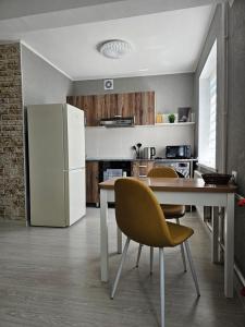 een keuken met een tafel en een witte koelkast bij Квартира-студия рядом с Набережной in Balqash +8 foto's