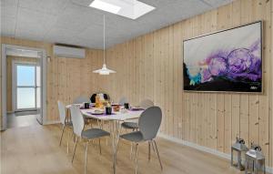 a dining room with a table and chairs and a painting at Holiday Home Fyrgården Blåvand in Blåvand