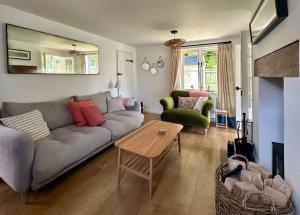 een woonkamer met een bank en een tafel bij Holly Cottage in Cirencester