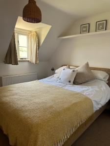 een slaapkamer met een bed met witte lakens en kussens bij Holly Cottage in Cirencester