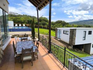 Un patio con una mesa y sillas en un balcón. en Finca Hotel Posada La Riviera, en Moniquirá