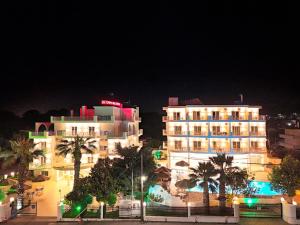 a hotel at night with palm trees in front of it at Olympion Melathron in Platamonas