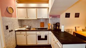 a kitchen with white cabinets and a sink at Ferienwohnung Am Mühlenbach in Bienenbüttel