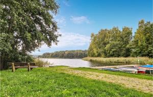 a bench next to a river with boats on it at Stunning Stacaravan In Lohmen Am See in Garden +7 photos