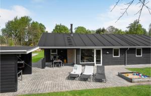 a house with a black roof and a patio at Holiday Home Næsehornsvej Ålbæk X in Ålbæk