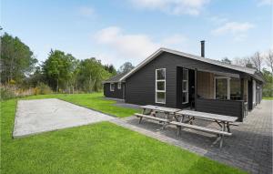 a black house with a picnic table and a bench at Holiday Home Næsehornsvej Ålbæk X in Ålbæk