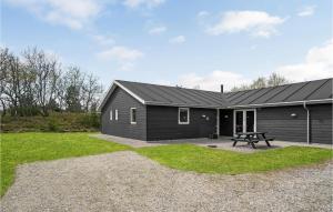 a black house with a picnic table in a yard at Holiday Home Næsehornsvej Ålbæk X in Ålbæk