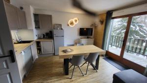 a small kitchen with a wooden table and chairs at Appartement 4 à 6 personnes - Chalets d'Aurouze - La Joue du Loup in Le Dévoluy