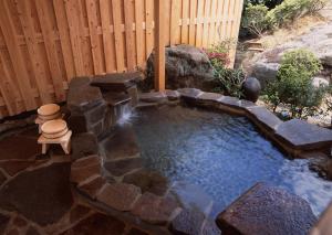 uma pequena piscina de água com uma parede de pedra em Misakitei em Kami Amakusa