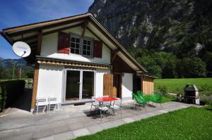 ein kleines Haus mit Stühlen, einem Tisch und einem Grill in der Unterkunft Waterfall Chalet in Stechelberg