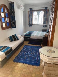 um quarto com duas camas, um sofá e uma mesa em Riad Aicha em Arzila mais 29 fotografias